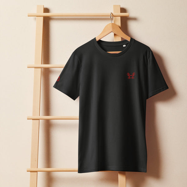 Unisex Bio-T-Shirt in Schwarz mit rot gesticktem Krabbenmotiv auf Holzleiter-Halterung.