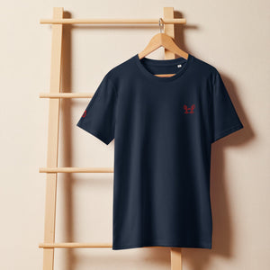 Krabbe unisex bio t-shirt aus Bio-Baumwolle mit eleganter Stickerei, hängend an einem Holzregal.